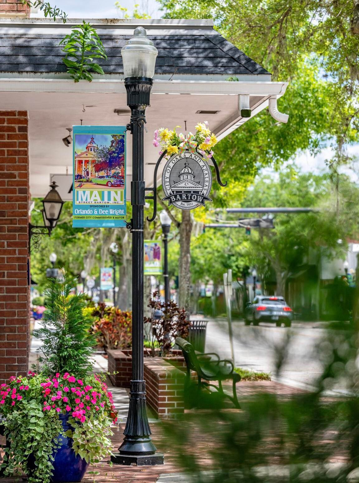 Downtown street with ornate lamp post, Main Street Bartow banners, flower baskets, and brick storefronts